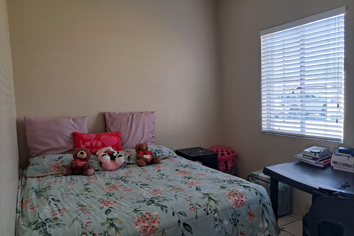 A bedroom featuring tiled flooring and horizontal window blinds, providing a functional space with natural light.