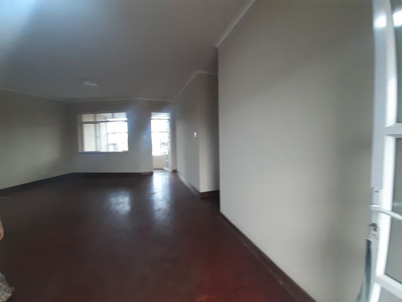Spacious, empty living area featuring polished parquet flooring, neutral wall finishes, and coved cornicing, offering a blank canvas for interior design.