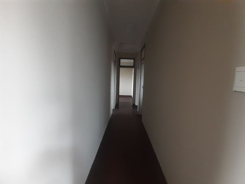 A simple, empty interior hallway connecting multiple rooms within the flat.