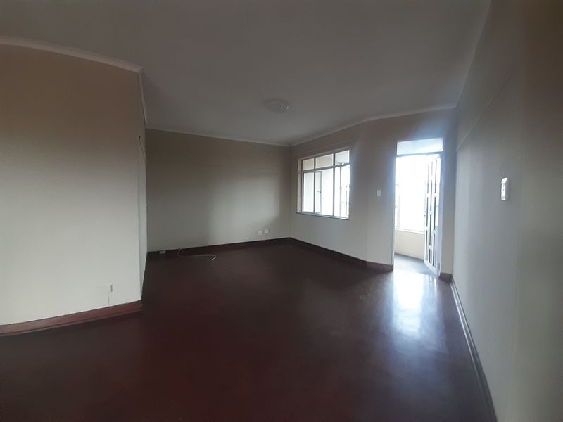 An empty living room featuring dark parquet flooring, coved cornicing, and direct access to an outdoor balcony area.