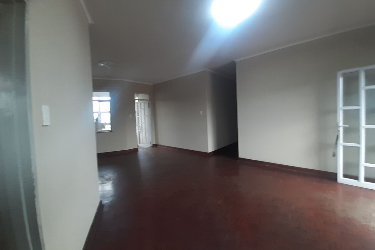 An empty, open-plan living area featuring tiled flooring and coved cornicing, providing a blank canvas for potential interior design updates.