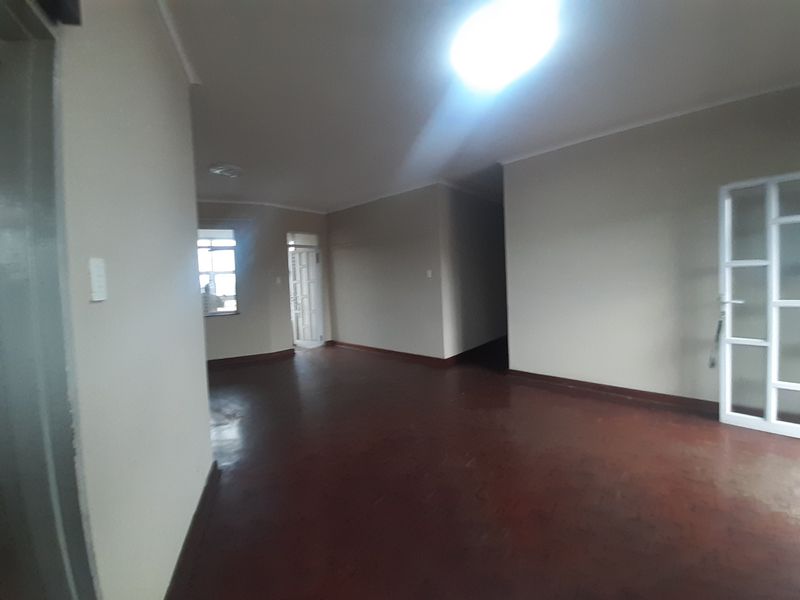 An empty, open-plan living area featuring tiled flooring and coved cornicing, providing a blank canvas for potential interior design updates.