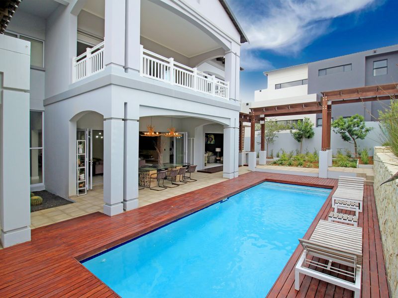 A well-maintained outdoor entertainment area featuring a swimming pool, timber decking, a covered patio, and a pergola, perfect for relaxation and hosting.