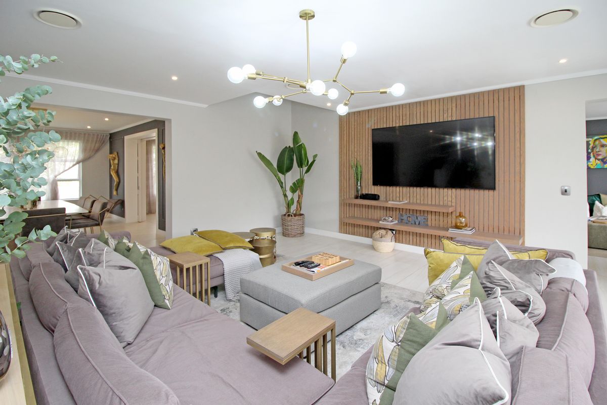 Spacious living room featuring a contemporary timber slat feature wall with integrated floating shelving and modern lighting.