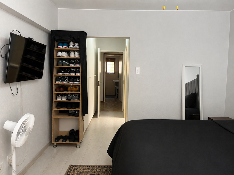 A bedroom featuring light-toned laminate flooring and a doorway leading to an adjacent bathroom area.