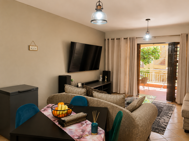 Open plan living area featuring ceramic floor tiles, pendant lighting, and direct access to a private balcony through sliding glass doors.
