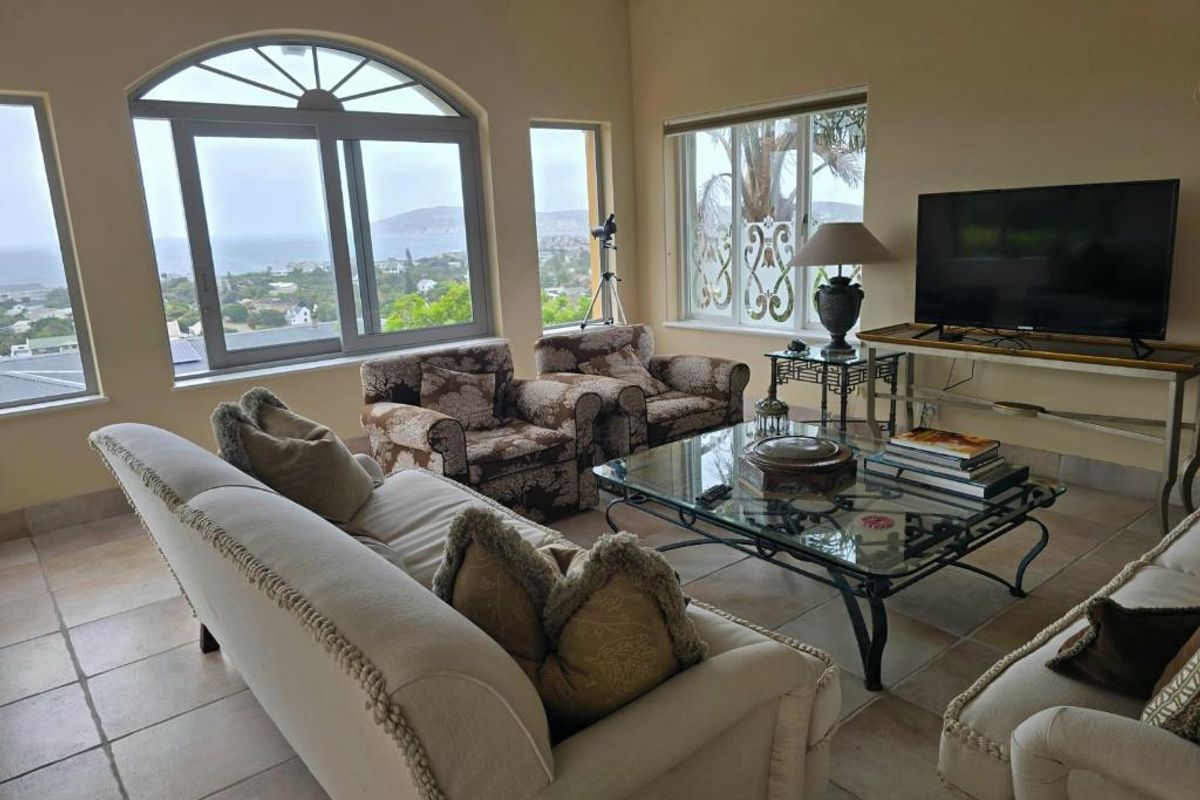 Spacious living room featuring large windows with scenic coastal views and neutral tiled flooring.