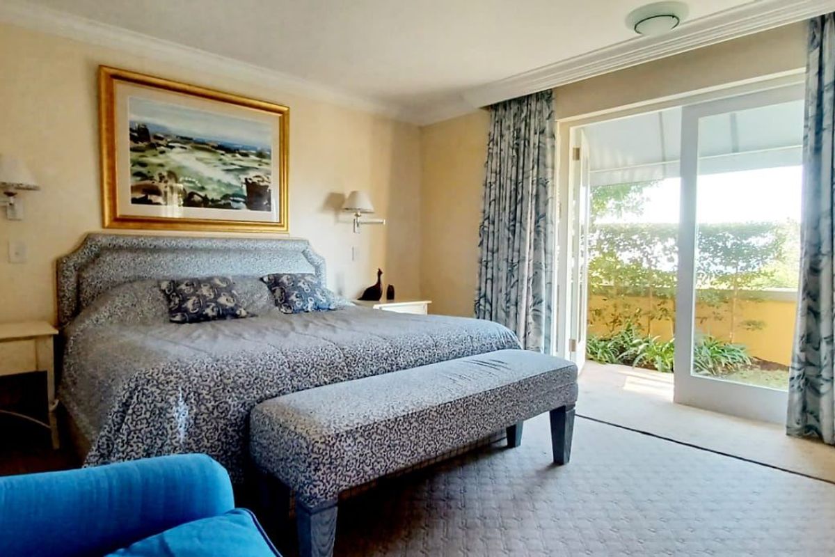 Spacious bedroom featuring crown molding, wall-mounted lighting, and large sliding glass doors providing direct access to an outdoor patio area.