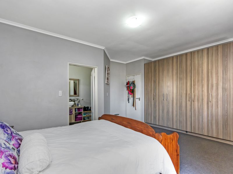 Spacious bedroom featuring extensive built-in wooden cabinetry, neutral wall finishes, and direct access to an en-suite bathroom.