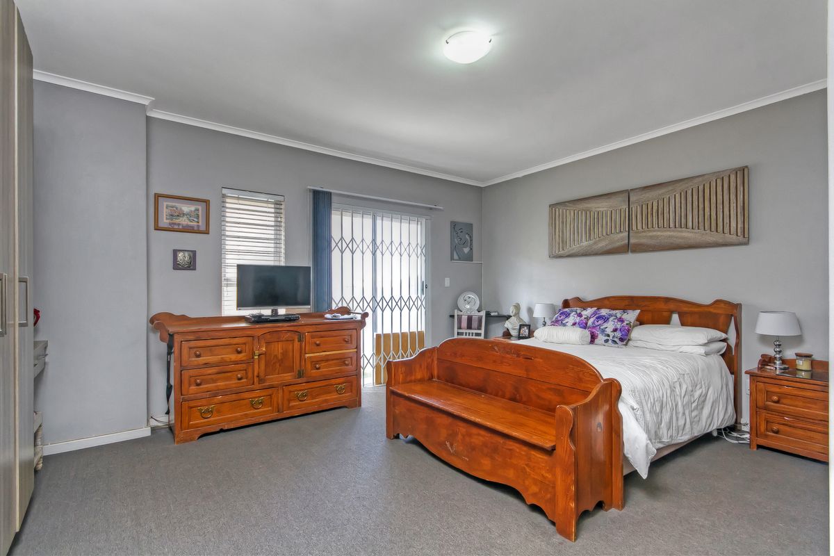 Spacious bedroom featuring neutral grey walls, carpeted flooring, built-in storage, and direct access to an outdoor area through a sliding glass door.
