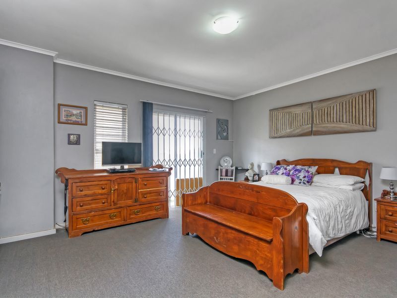 Spacious bedroom featuring neutral grey walls, carpeted flooring, built-in storage, and direct access to an outdoor area through a sliding glass door.