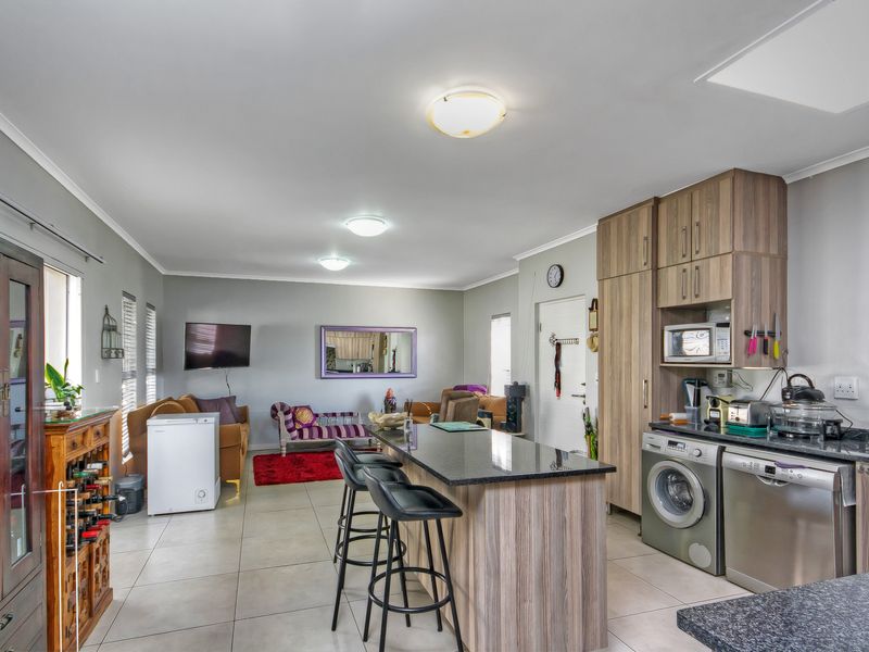 Open-plan living area featuring a kitchen with granite countertops, built-in cabinetry, and a central island, seamlessly flowing into the lounge space.