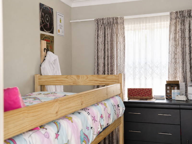 A bedroom featuring neutral wall tones, coving, and a window dressed with patterned curtains.