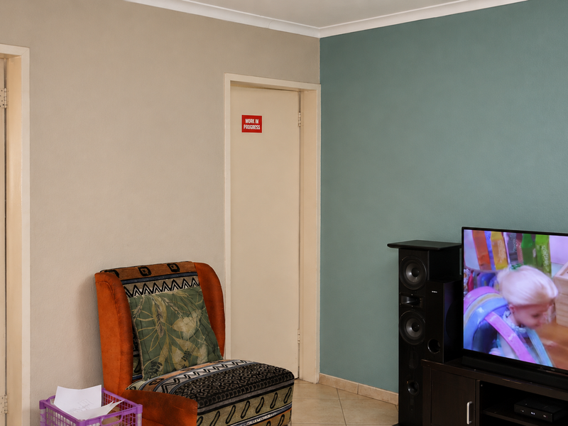 A living room area featuring tiled flooring, coving, and dual-tone painted walls, providing a functional space for relaxation.