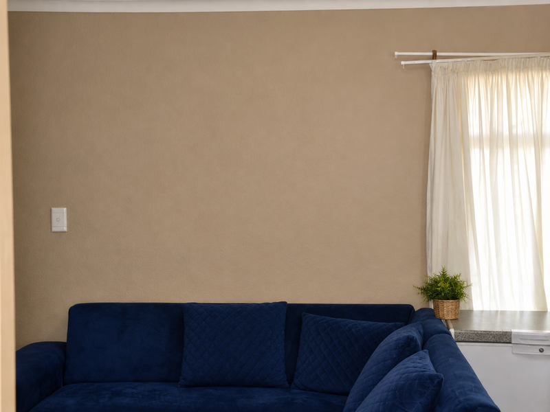 A view into a living room space featuring neutral wall tones and a window with installed curtain rails.