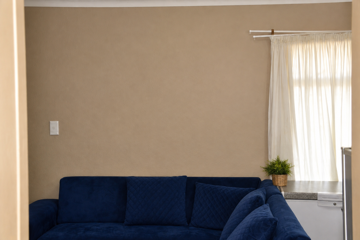 A view into a living room space featuring neutral wall tones and a window with installed curtain rails.