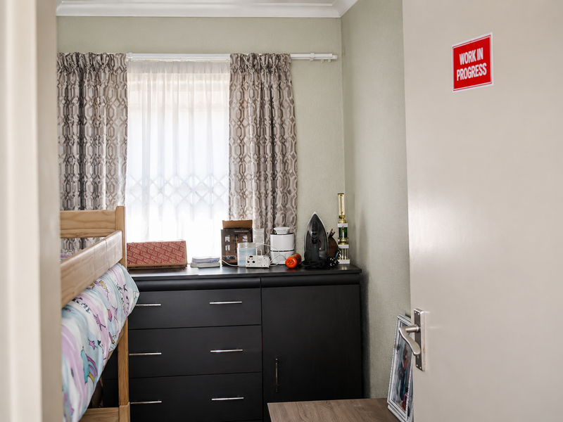 A bedroom featuring a window with security gate and curtain rails, viewed from the doorway.
