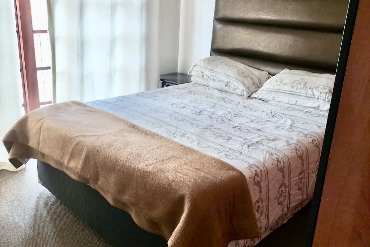 A bedroom featuring carpeted flooring and a glass-paneled french door providing natural light.