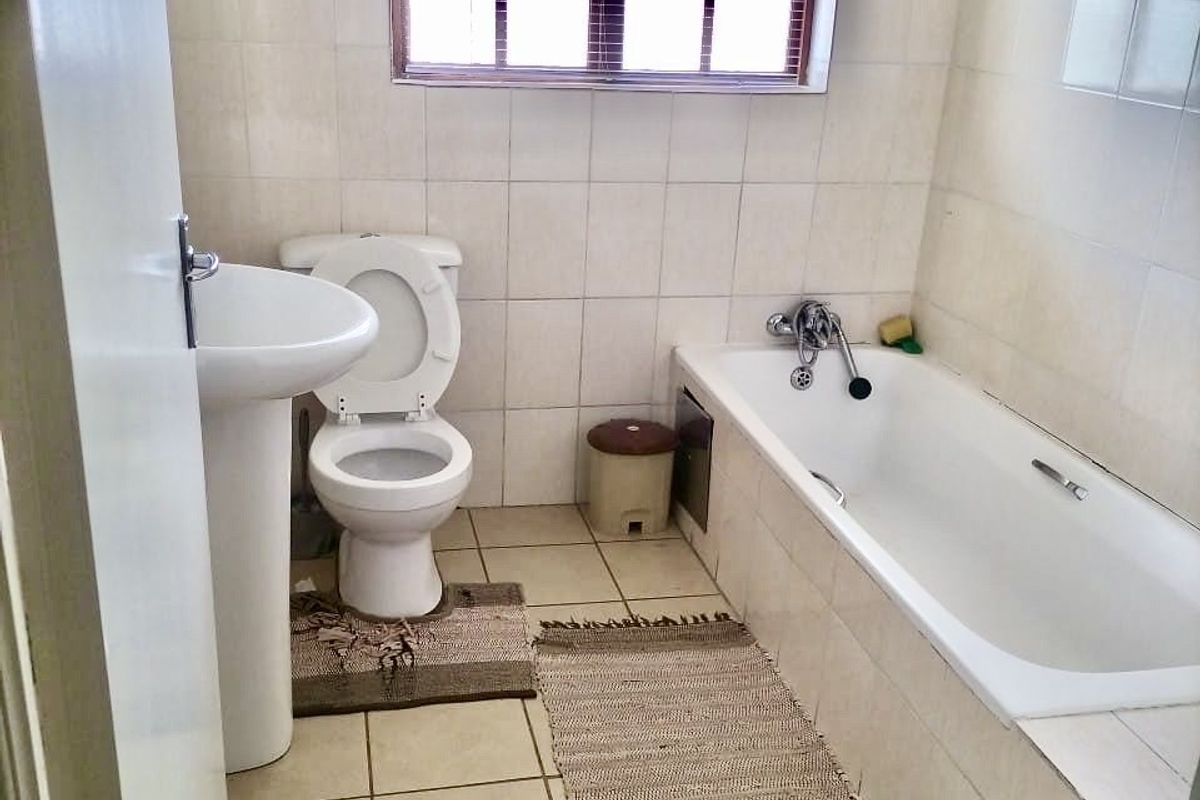 A functional bathroom featuring a pedestal basin, toilet, and bathtub with tiled finishes throughout.