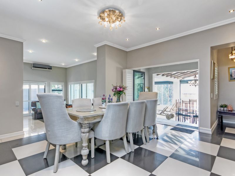Spacious dining area featuring high-contrast tiled flooring, recessed lighting, and seamless access to the outdoor patio through large sliding glass doors.