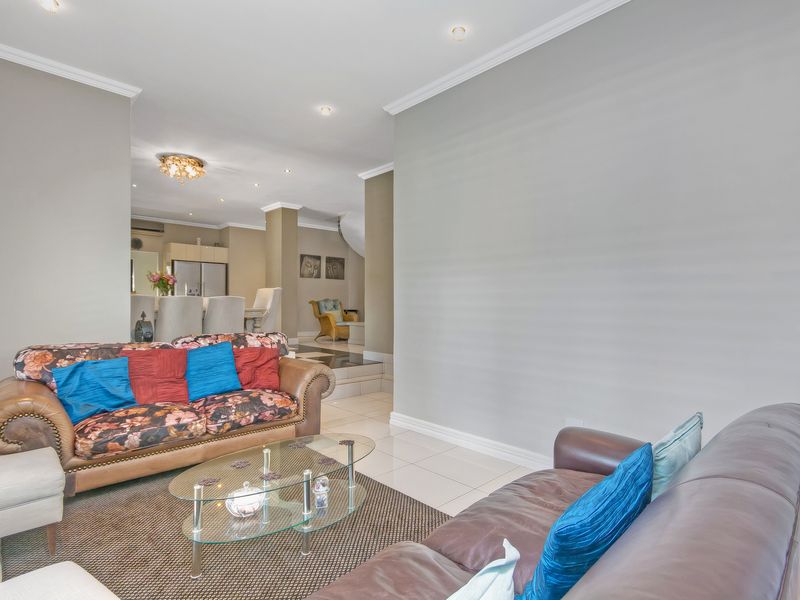 Spacious open-plan living area featuring neutral wall tones, tiled flooring, and recessed lighting, creating a seamless flow between the lounge and dining spaces.
