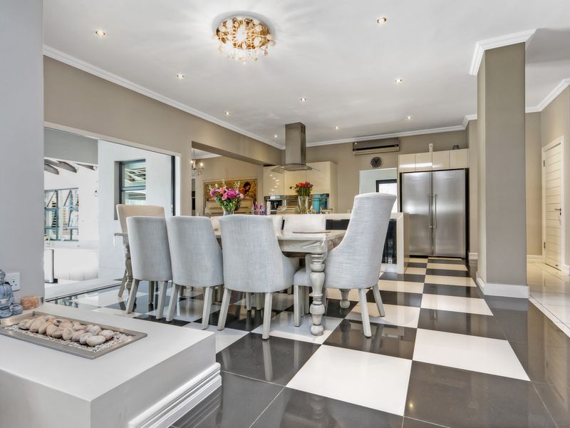Spacious open-plan living and dining area featuring high-contrast checkerboard tile flooring, modern cabinetry, and integrated lighting throughout the kitchen and dining space.