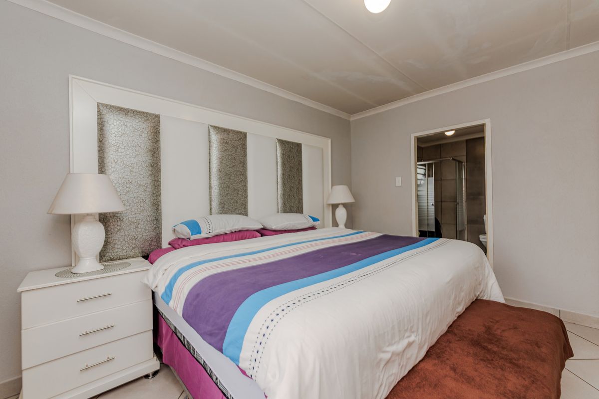 Spacious bedroom featuring a built-in headboard, tiled flooring, and an en-suite bathroom access point.