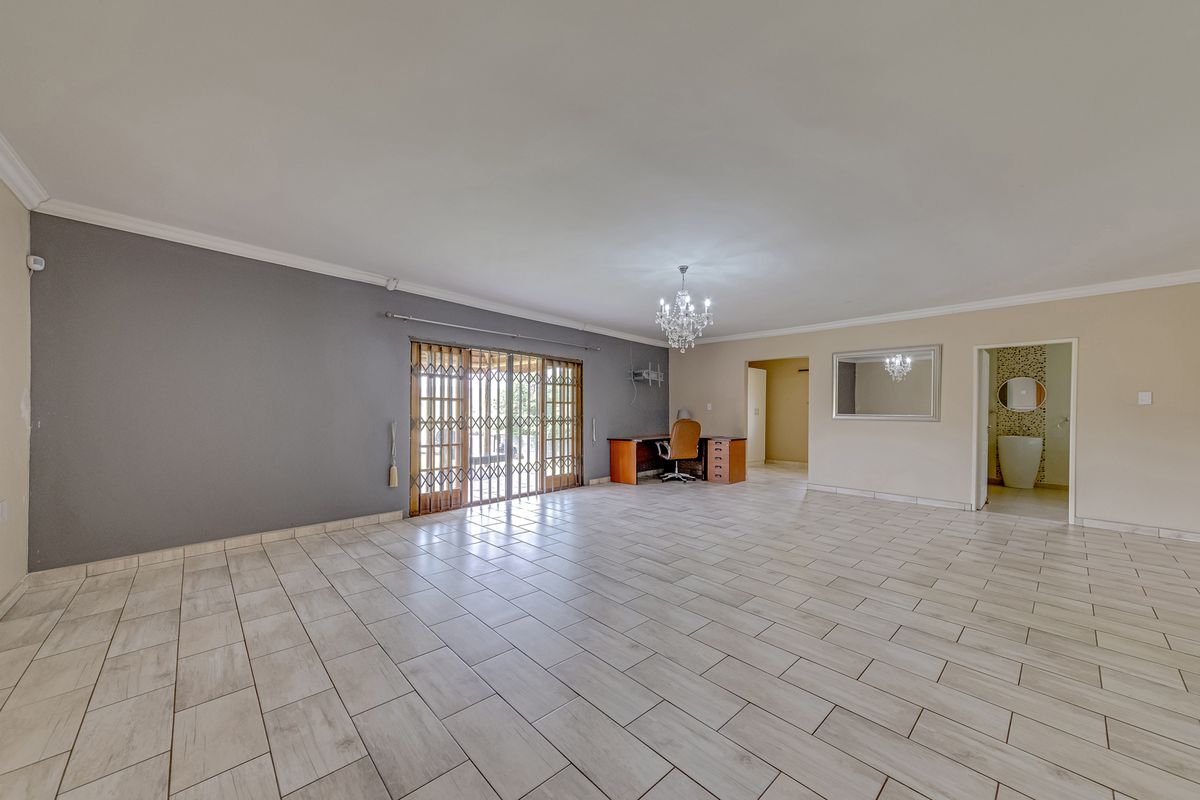 Spacious living area featuring neutral tiled flooring, modern grey accent wall, and sliding glass doors leading to the exterior.