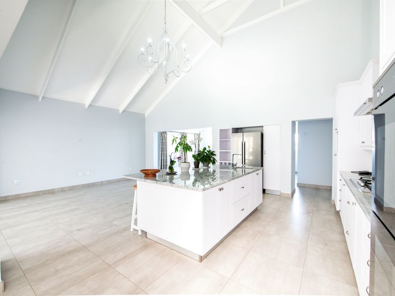 Spacious open-plan kitchen featuring a central island with granite countertops, vaulted ceilings, and modern built-in appliances, creating a bright and airy living space.