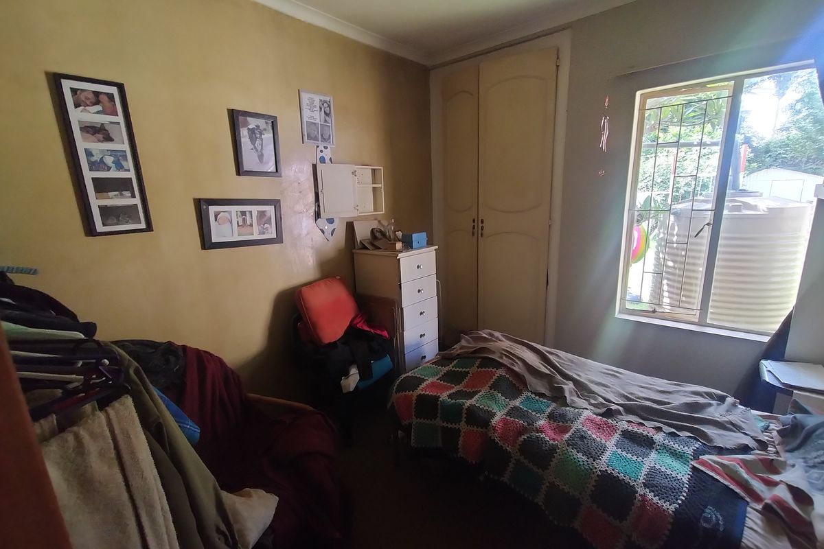 A bedroom featuring a built-in wardrobe and a window with security bars, requiring cosmetic updates to the wall finishes.