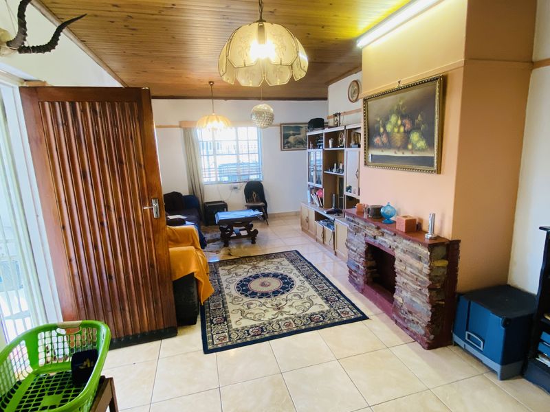 Living room featuring a stone-clad fireplace, tiled flooring, and a timber tongue and groove ceiling with integrated lighting.