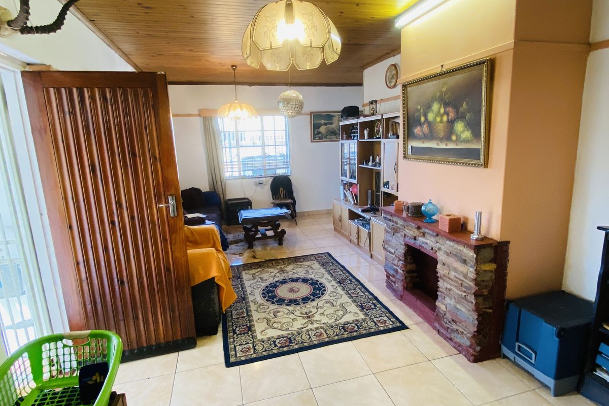 Living room featuring a stone-clad fireplace, tiled flooring, and a timber tongue and groove ceiling with integrated lighting.