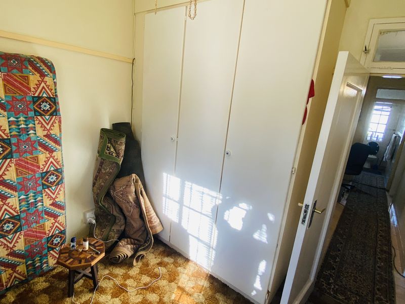A bedroom featuring a built-in wardrobe, ceiling fan, and dated carpet flooring, offering potential for modernization and cosmetic updates.