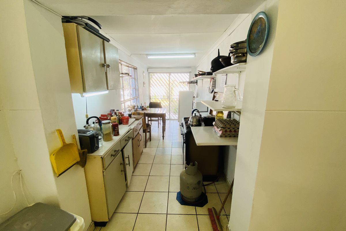 A functional galley-style kitchen featuring tiled flooring, built-in cabinetry, and a gas stove, with direct access to an outdoor area through a sliding door.