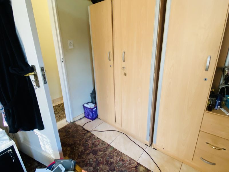 A bedroom featuring built-in wooden wardrobes and traditional coving, providing functional storage space within the room.