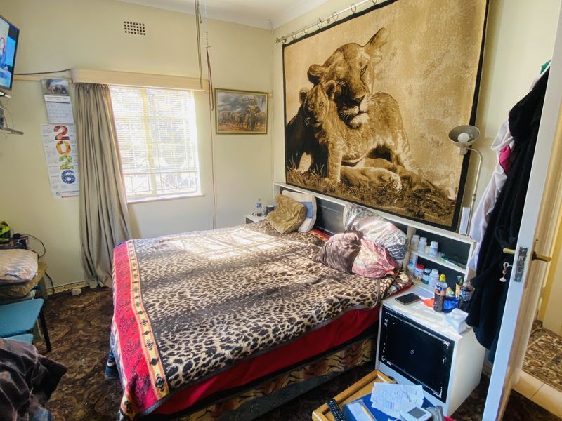 A bedroom featuring a ceiling fan, built-in headboard, and window. The room requires cosmetic updates to the flooring and ceiling finishes.