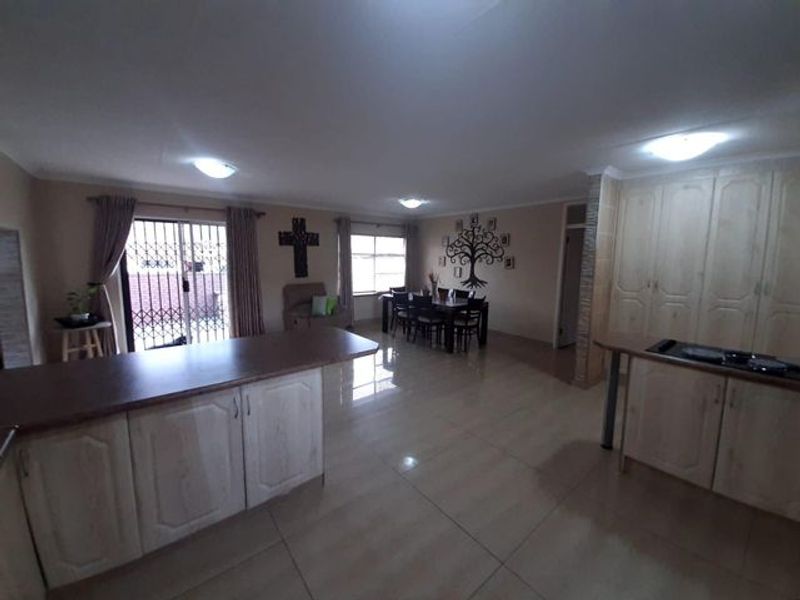 Spacious open-plan living and dining area featuring tiled flooring, built-in kitchen cabinetry, and sliding door access to the exterior.