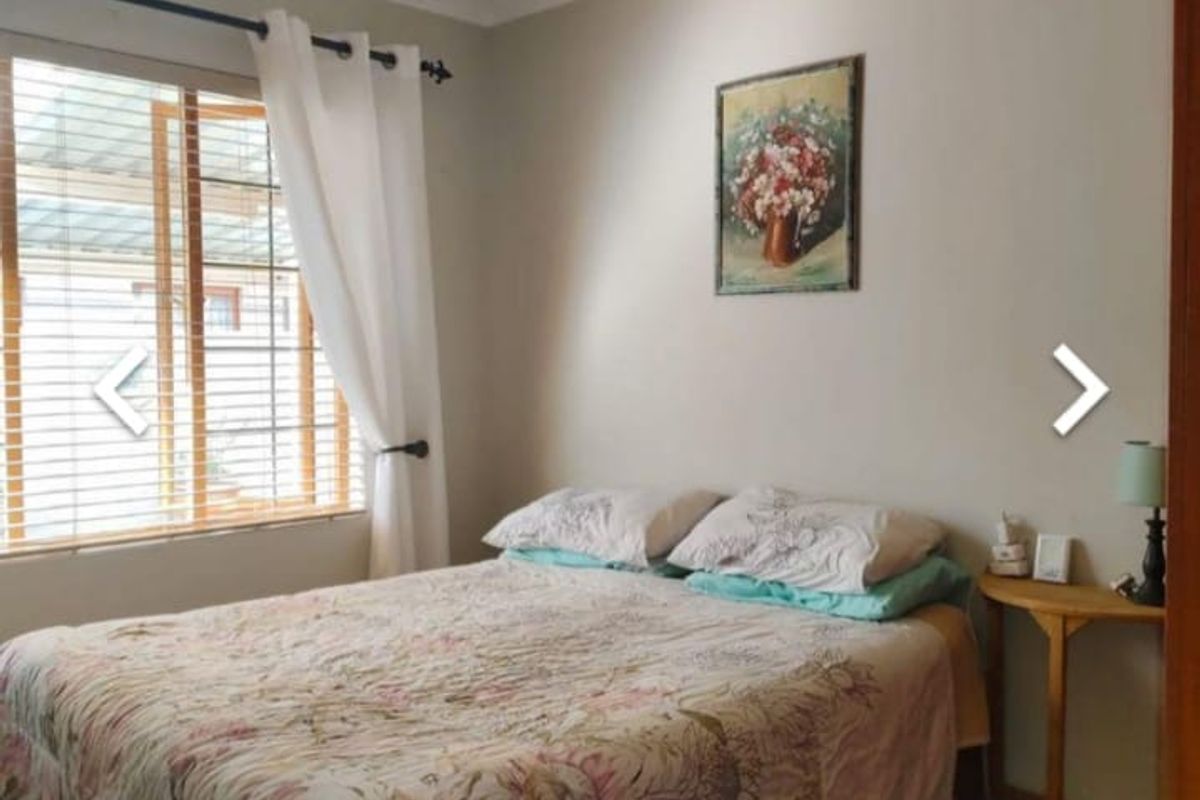 A standard bedroom featuring neutral wall finishes, a window with blinds, and a ceiling light fixture.