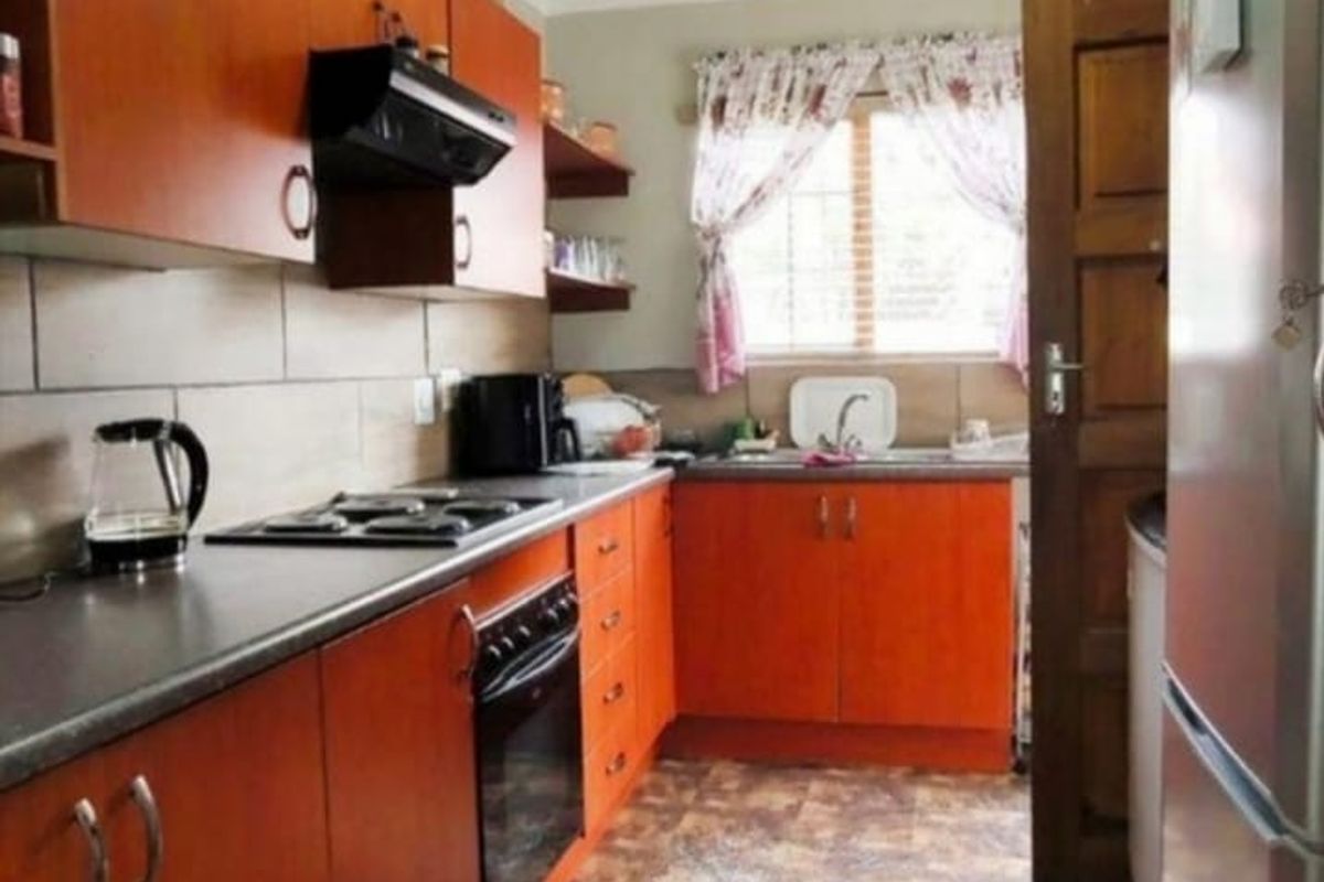 A functional kitchen featuring wood-tone cabinetry, built-in oven and hob, tiled backsplash, and a stainless steel sink.
