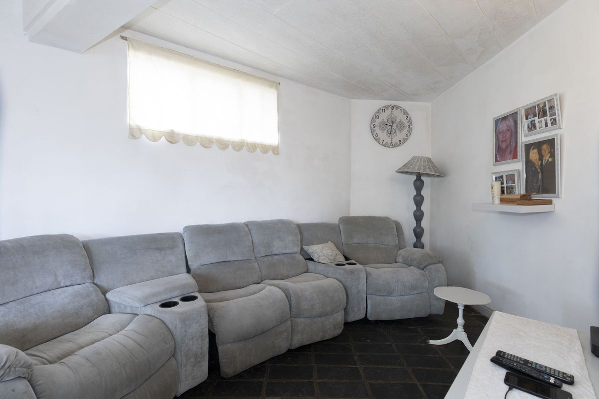 A living room featuring dark tiled flooring and a textured ceiling, providing a functional space ready for cosmetic updates and modern styling.