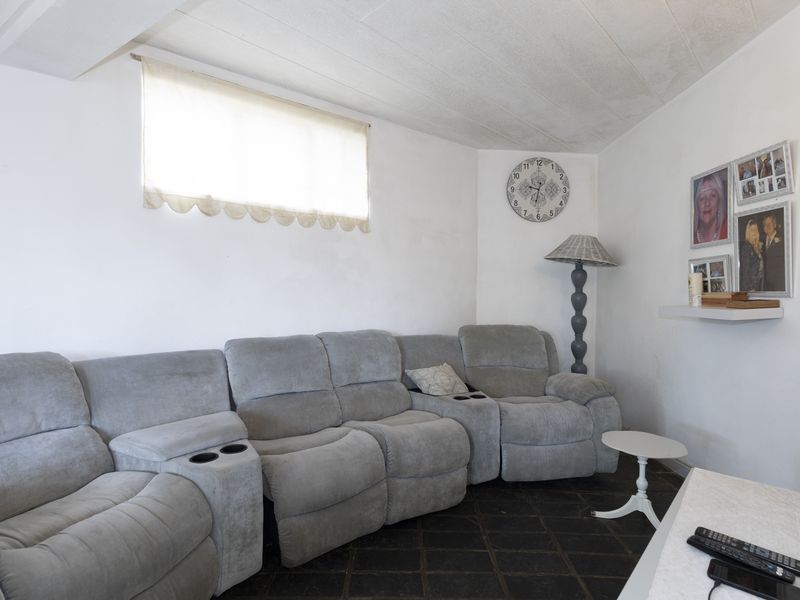 A living room featuring dark tiled flooring and a textured ceiling, providing a functional space ready for cosmetic updates and modern styling.
