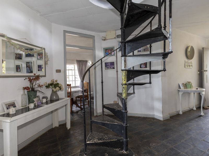 Entrance hall featuring a prominent black metal spiral staircase and dark tiled flooring, providing access to the adjoining living spaces.