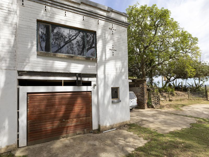 Exterior view of a detached garage structure featuring a roller door, brick facade, and adjacent concrete driveway area.