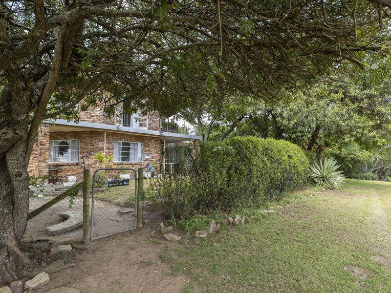 Front view of a face brick house featuring a gated entrance, security bars, and established garden surroundings.
