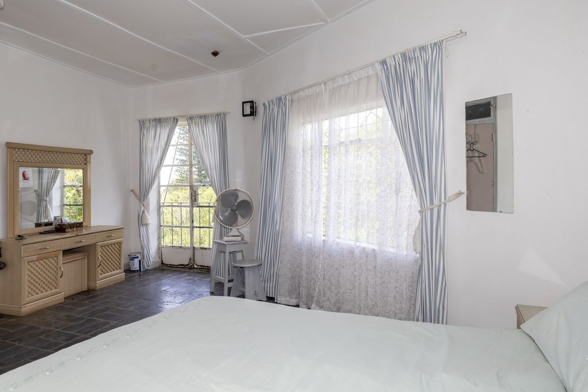 A bedroom featuring tiled flooring, security bars on windows, and a security gate leading to an outdoor area.