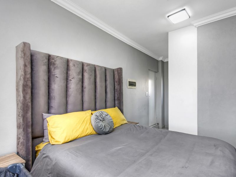 A well-maintained bedroom featuring crown molding, neutral grey walls, and a flush mount ceiling light fixture.