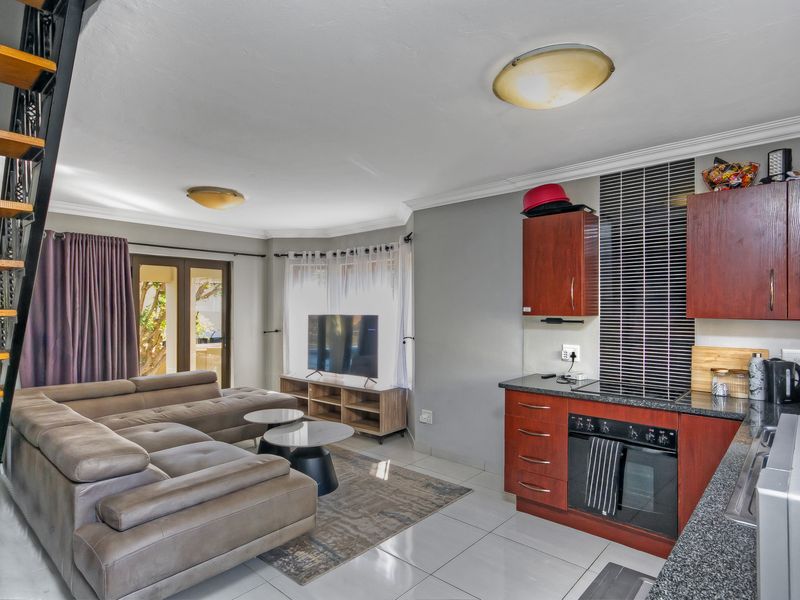 Open-plan living area featuring a kitchen with dark wood cabinetry, granite countertops, tiled floors, and direct access to an outdoor patio via sliding doors.