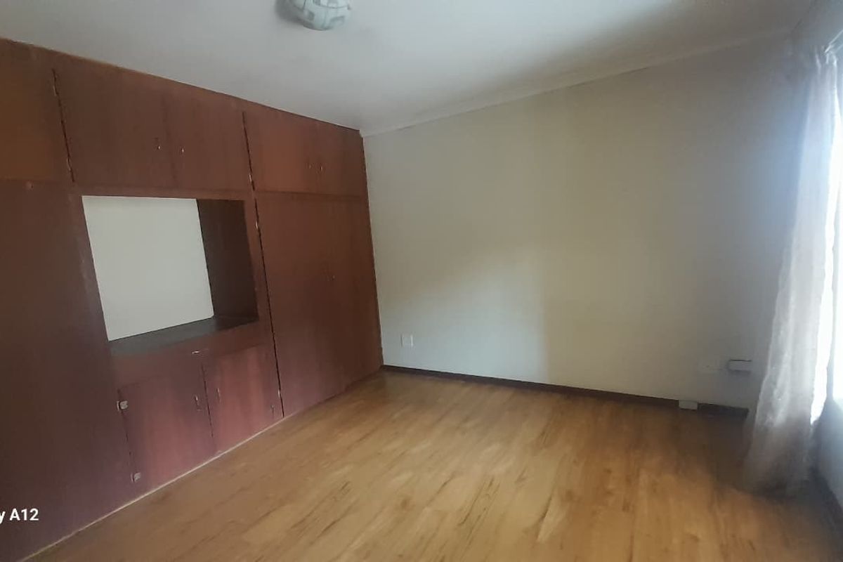 An empty bedroom featuring laminate flooring and extensive built-in wooden cabinetry, offering a blank canvas for potential interior updates.