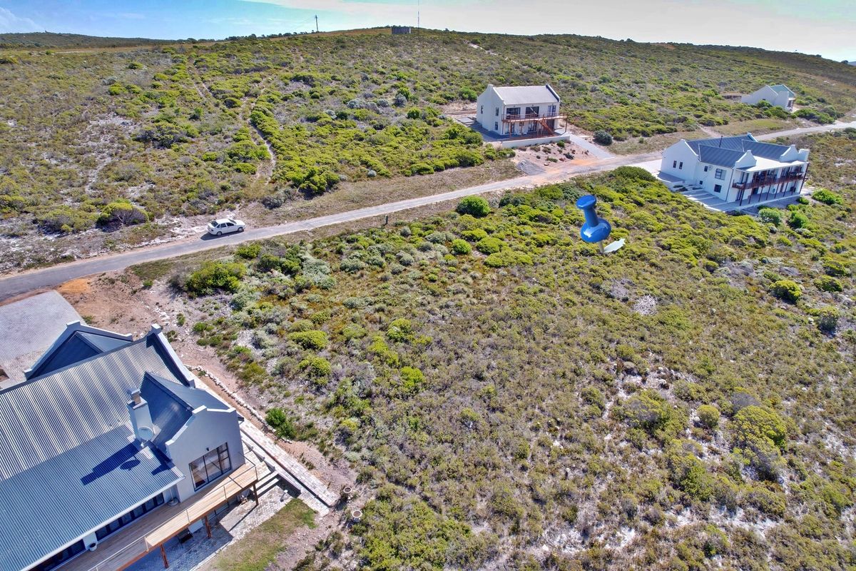 Aerial view of a vacant residential plot situated in a coastal estate, surrounded by established homes and natural fynbos vegetation.