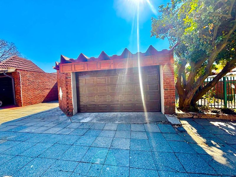 A detached brick garage featuring a sectional door and paved driveway, set within a residential property exterior.